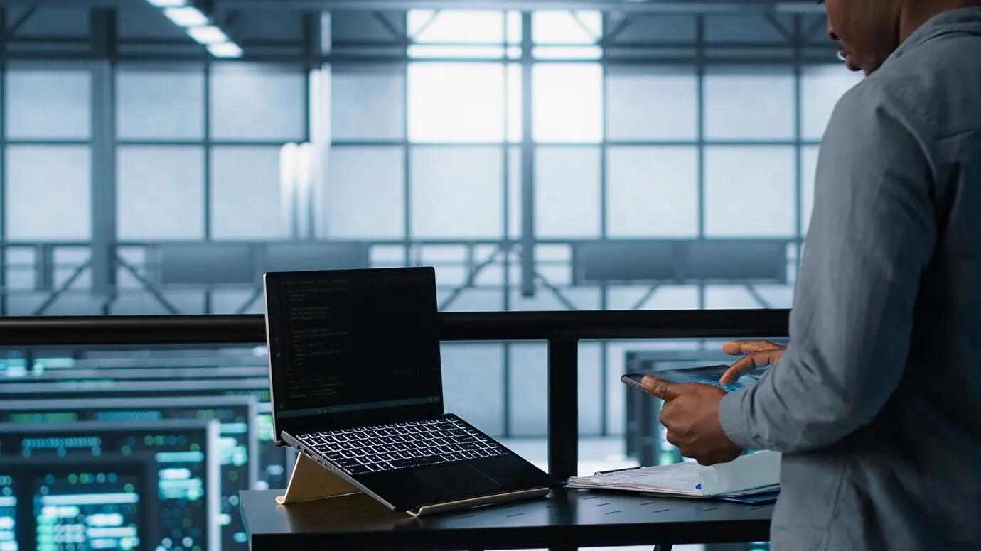 Мужчина в серверной ферме применяет ИИ на устройствах для повышения производительности.