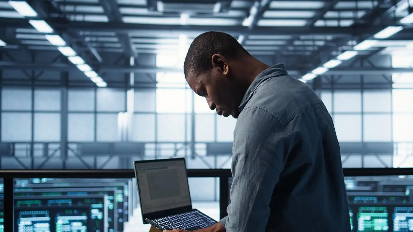 Инженер в центре обработки данных использует ноутбук для развертывания новых серверных архитектур.